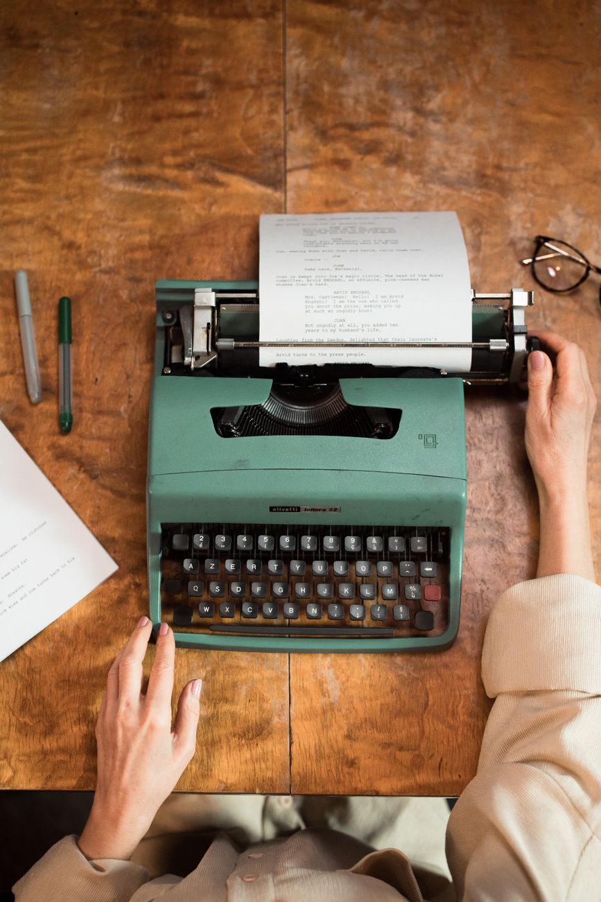 Hands typing on a vintage typewriter on a wooden desk