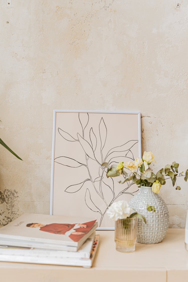 A Flower Vase Beside A Stack Of Books And Frame