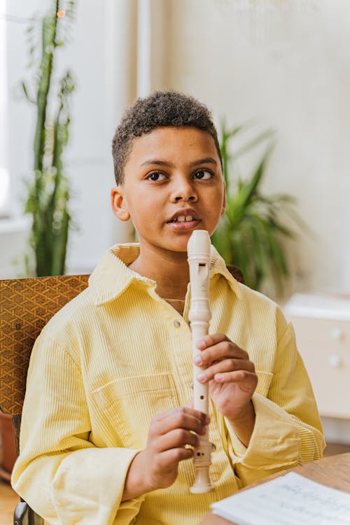 Free Photo of a Boy in a Yellow Shirt Playing a White Flute Stock Photo