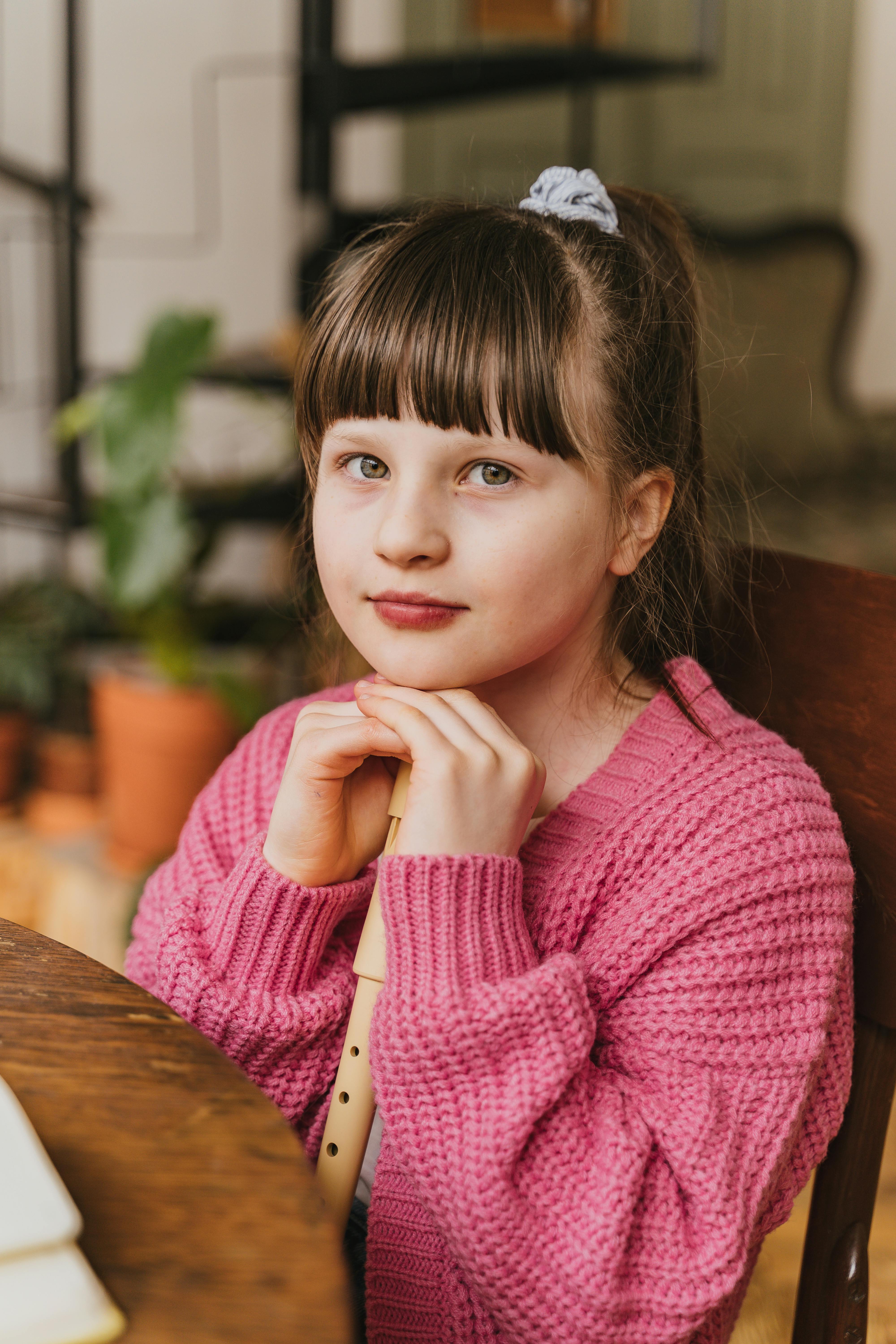 a pretty girl in pink sweater sitting on the chair