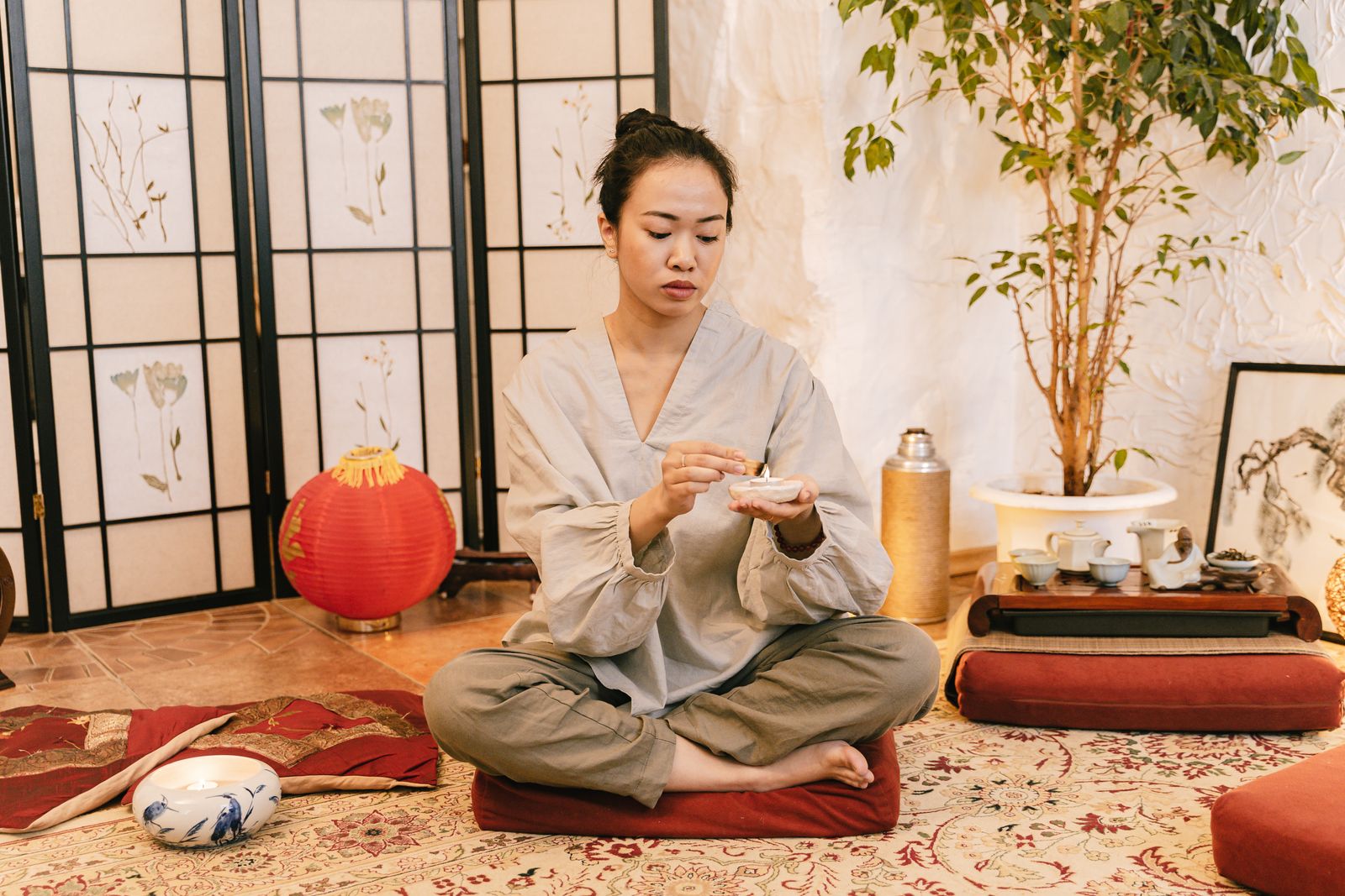 Woman meditating calmly with a candle in a tranquil indoor setting