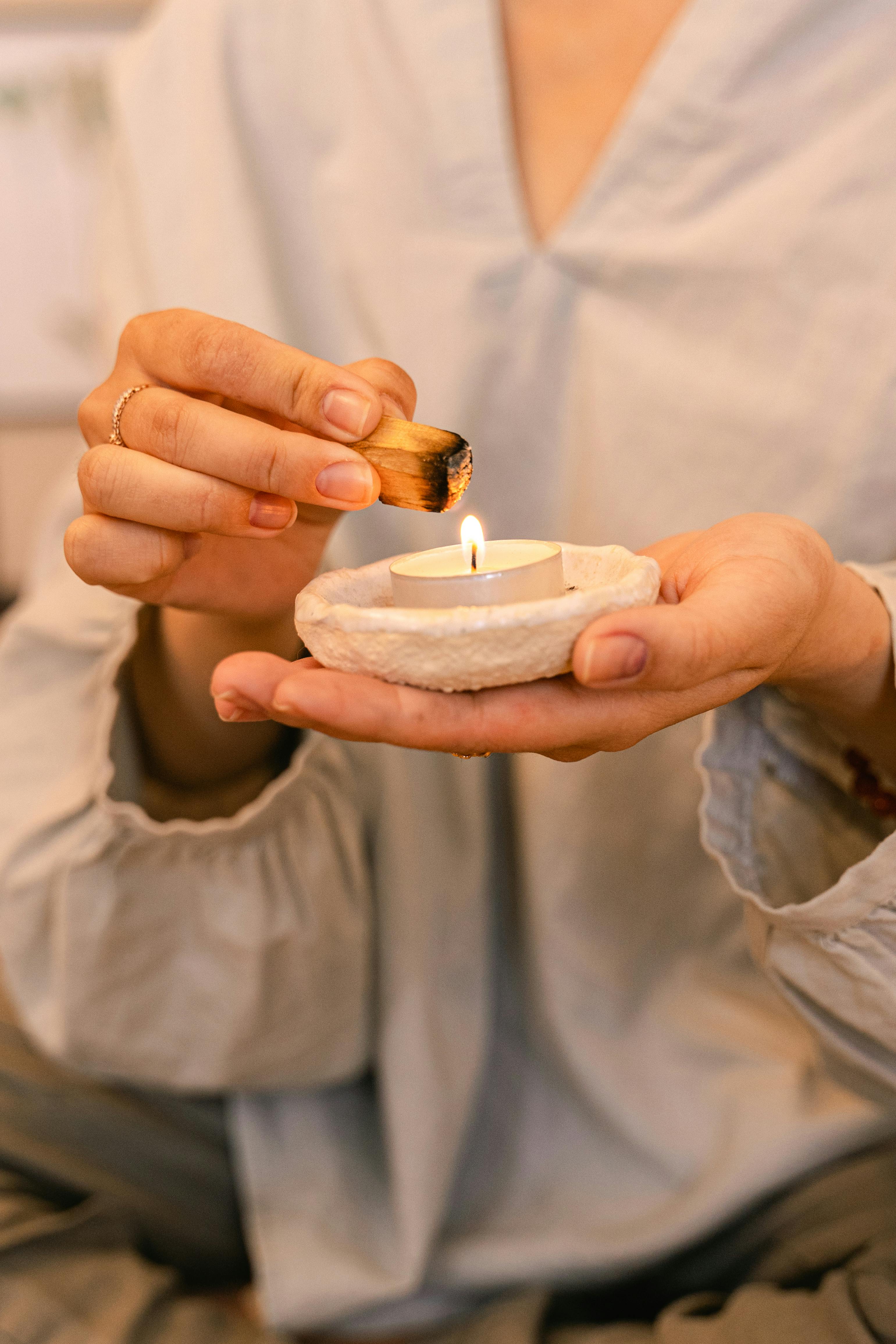 Relaxing scene of a person lighting a candle with sage for a peaceful ritual.