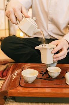 Close-up of hands pouring tea in a traditional ceremony setup. Relaxing and cultural experience.