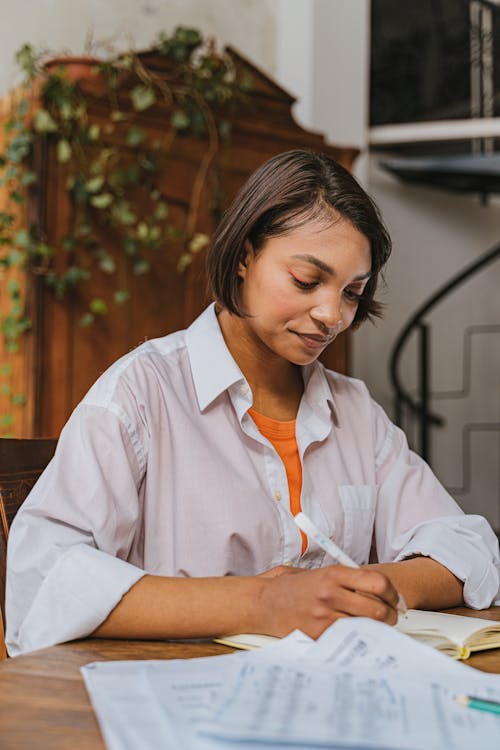 Free Woman Writing on Notebook with a Pen Stock Photo