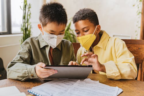 Free Children Wearing Face Masks Looking at the Screen of  Tablet Stock Photo