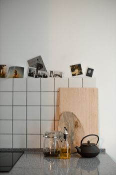 A minimalist kitchen counter with a cutting board, a kettle, and polaroid pictures.