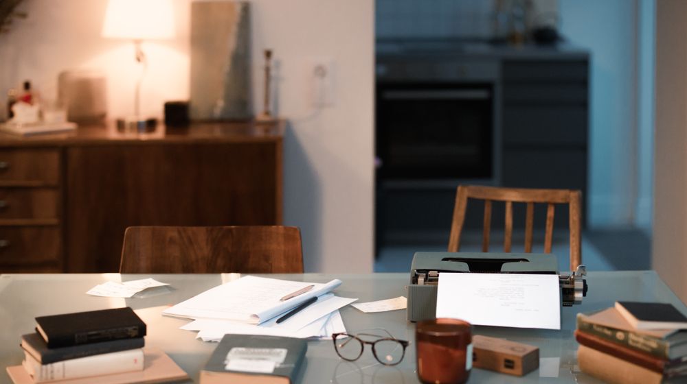 A warm and inviting home workspace featuring a typewriter, books, and ambient lighting for creative writing.