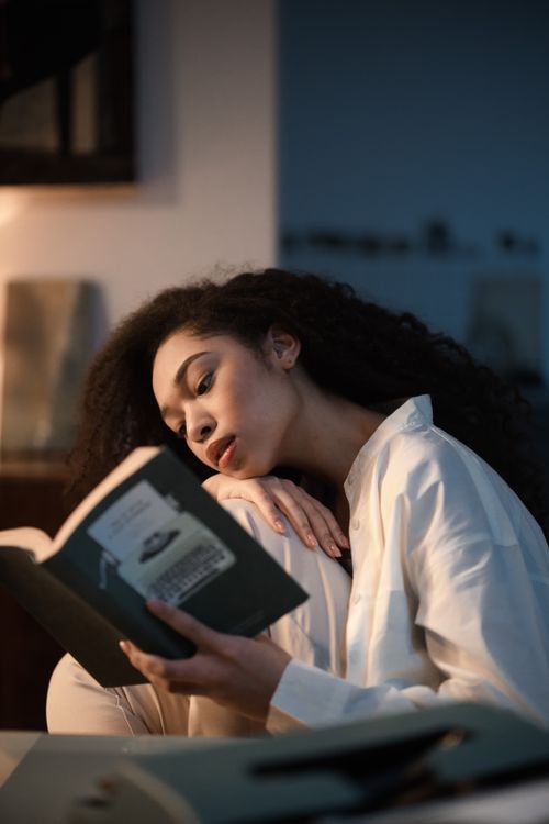 Free Woman enjoying a peaceful evening reading a book indoors Stock Photo