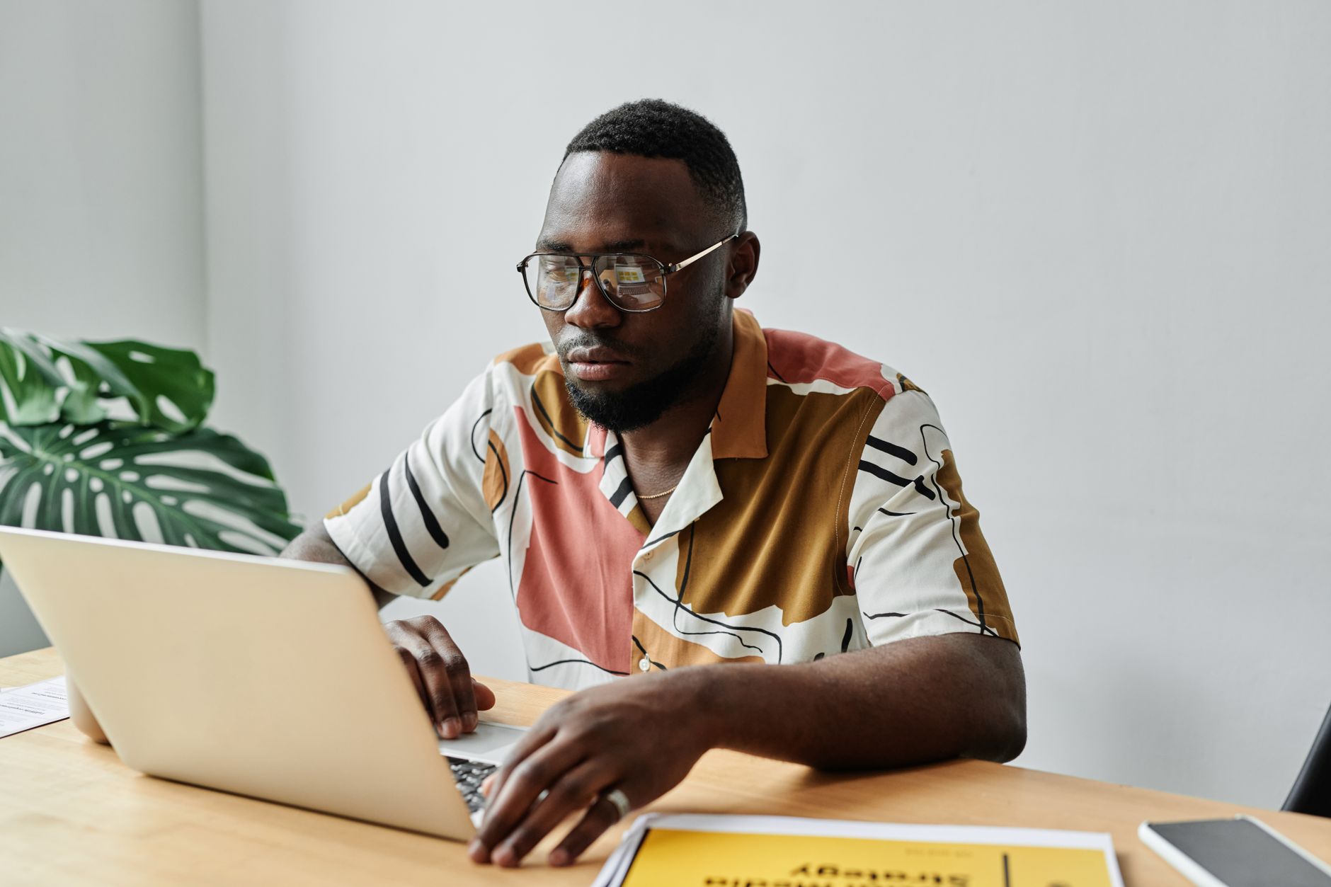 African American man using a laptop and working at a desk in an office setting.