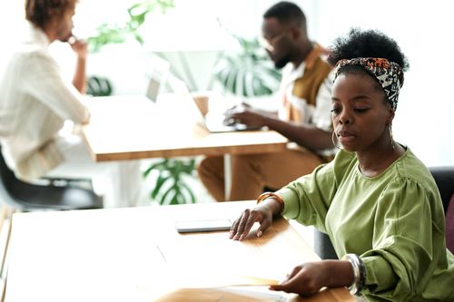 Free A focused woman working in a modern office environment with colleagues in the background. Stock Photo