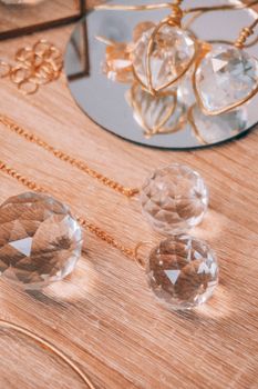 Close-up of sparkling crystal ornaments on a wooden table with mirrored reflections.