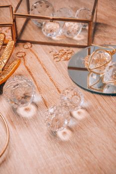 Luxurious crystal and gold jewelry captured on a reflective mirror with wooden background.