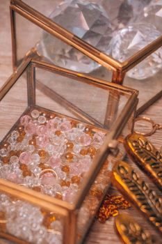 Elegant display of jewelry and gemstones in glass boxes on a wooden surface, exuding luxury.