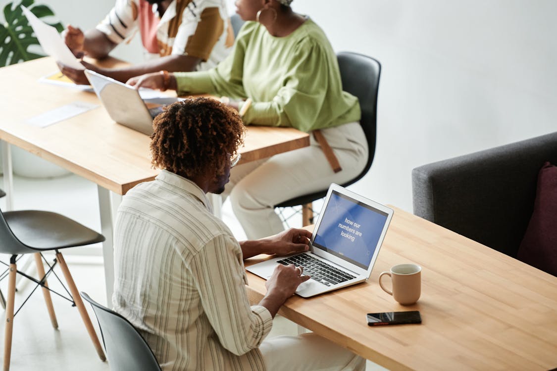 Free Man In White And Gray Stripe Shirt Using Macbook Pro Stock Photo