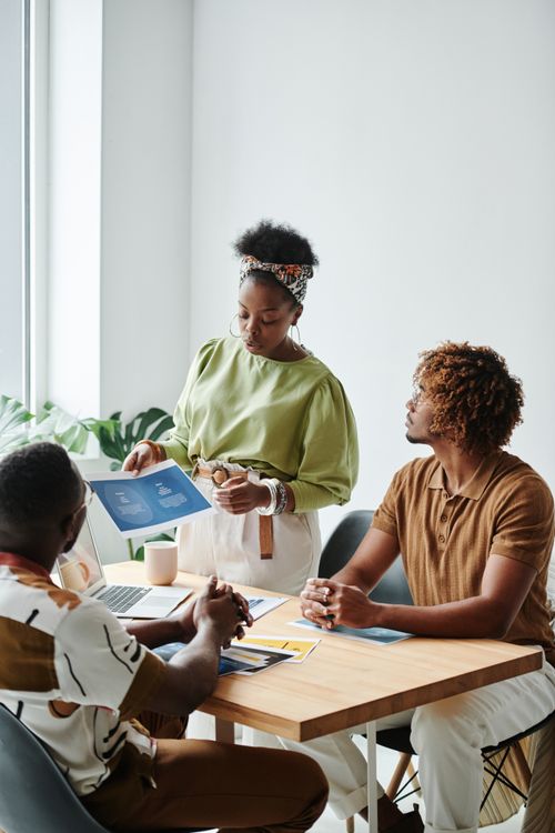 Free Diverse team collaborating in a bright, modern office setting with documents. Stock Photo