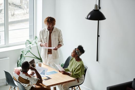 Group of diverse adults collaborating in a modern office setting, discussing business plans.