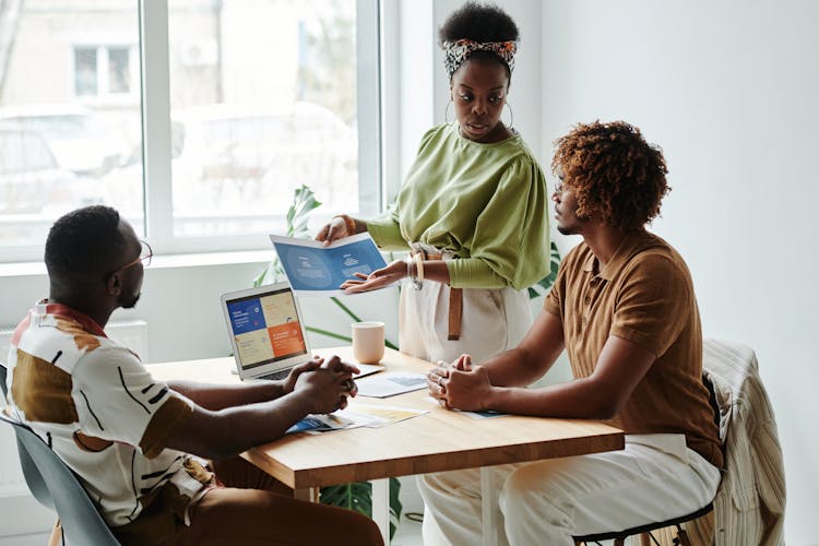 Woman Holding A Paper While Talking To Her Colleagues