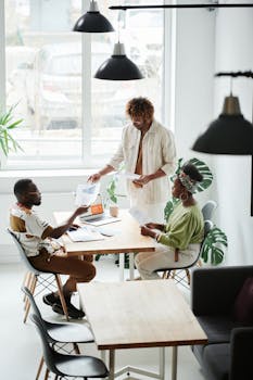 Three colleagues discussing papers in a bright office, showcasing teamwork and collaboration.