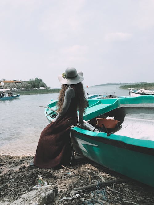 Stylish woman in hat sitting on boat