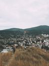 Distant people standing on grassy hilltop with waving Turkish flag hanging on flagpole above town