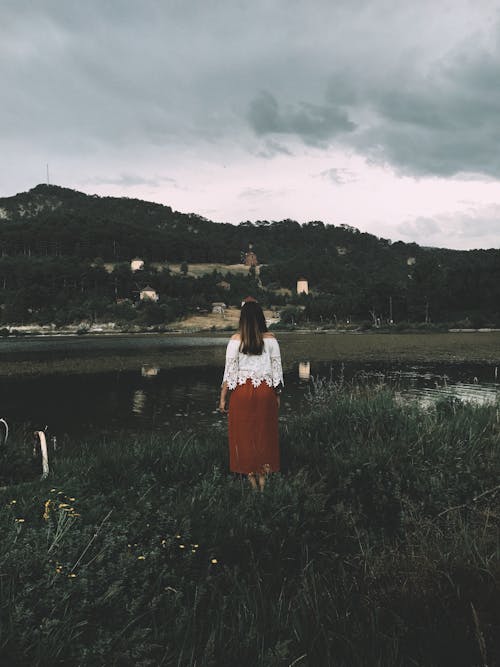 Woman standing on grassy shore of river