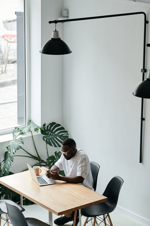 Free High-Angle Shot of a Man in a White Shirt Working on His Laptop Stock Photo