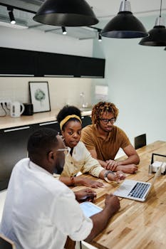 Diverse team collaborating in a modern office with laptops and discussions.