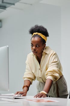 African American woman working focused at a computer in a modern office space.