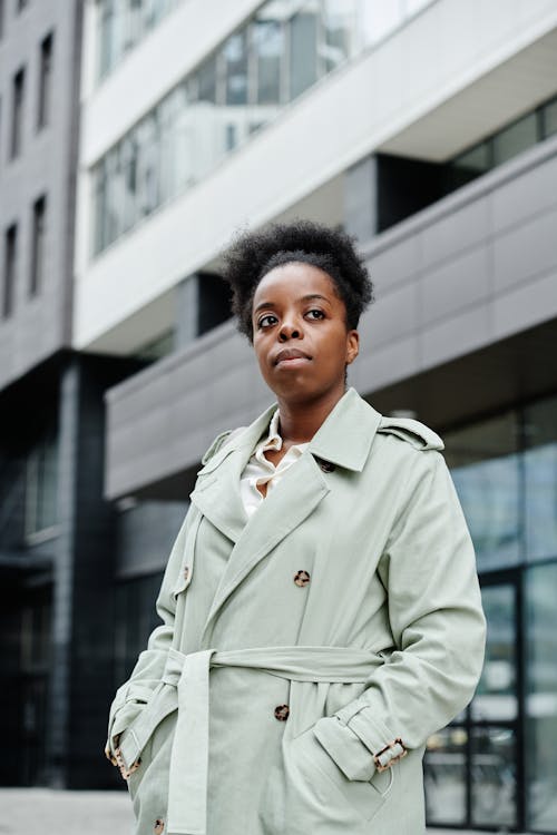 Free Woman in Gray Trench Coat Standing Near Building Stock Photo