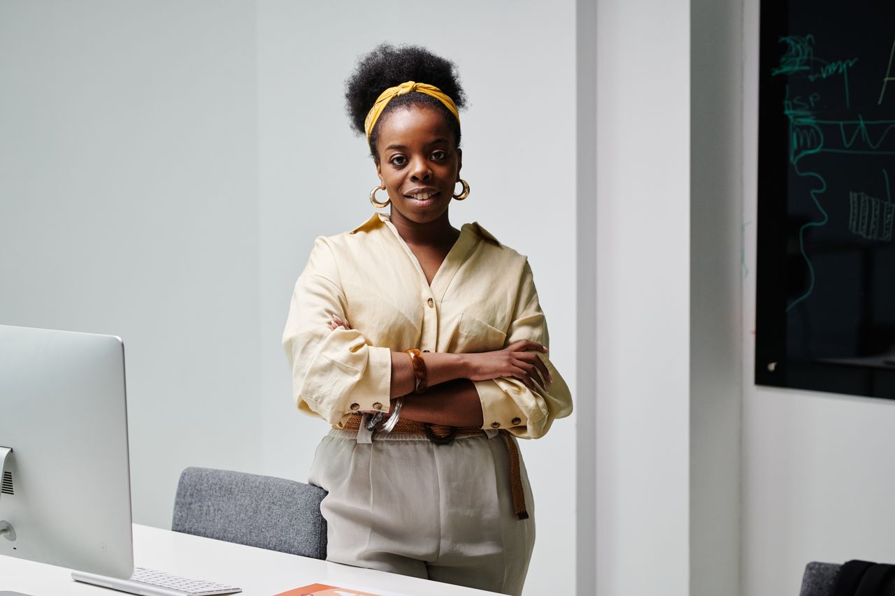 confident black woman with curly hair and headwrap smiling in a modern