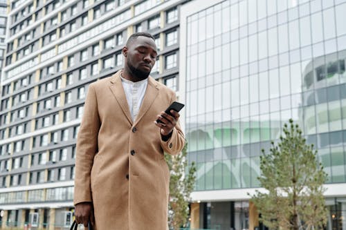 A Man in Brown Coat Using a Smartphone