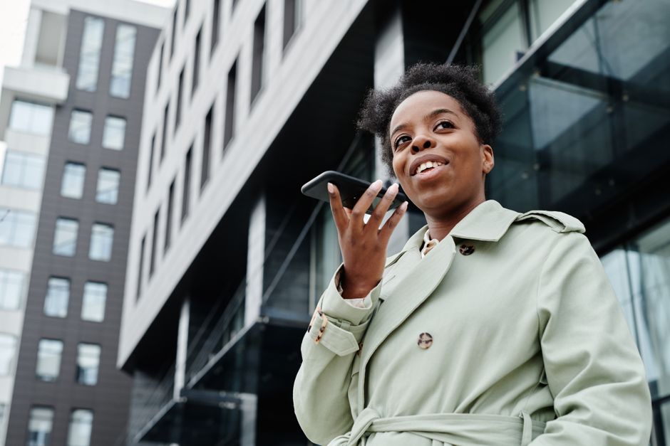 Confident woman in a trench coat makes a phone call in an urban environment.