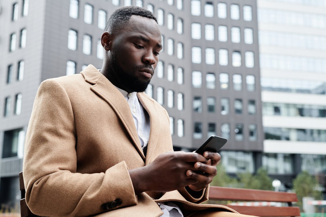 Selective Focus Photo of a Businessman in a Brown Suit Using His Cell Phone