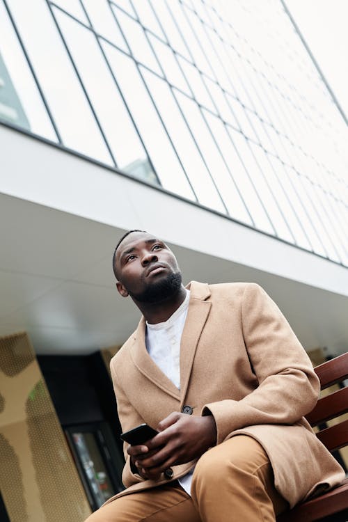 Free Low-Angle Shot of a Man in a Brown Coat Looking Away Stock Photo