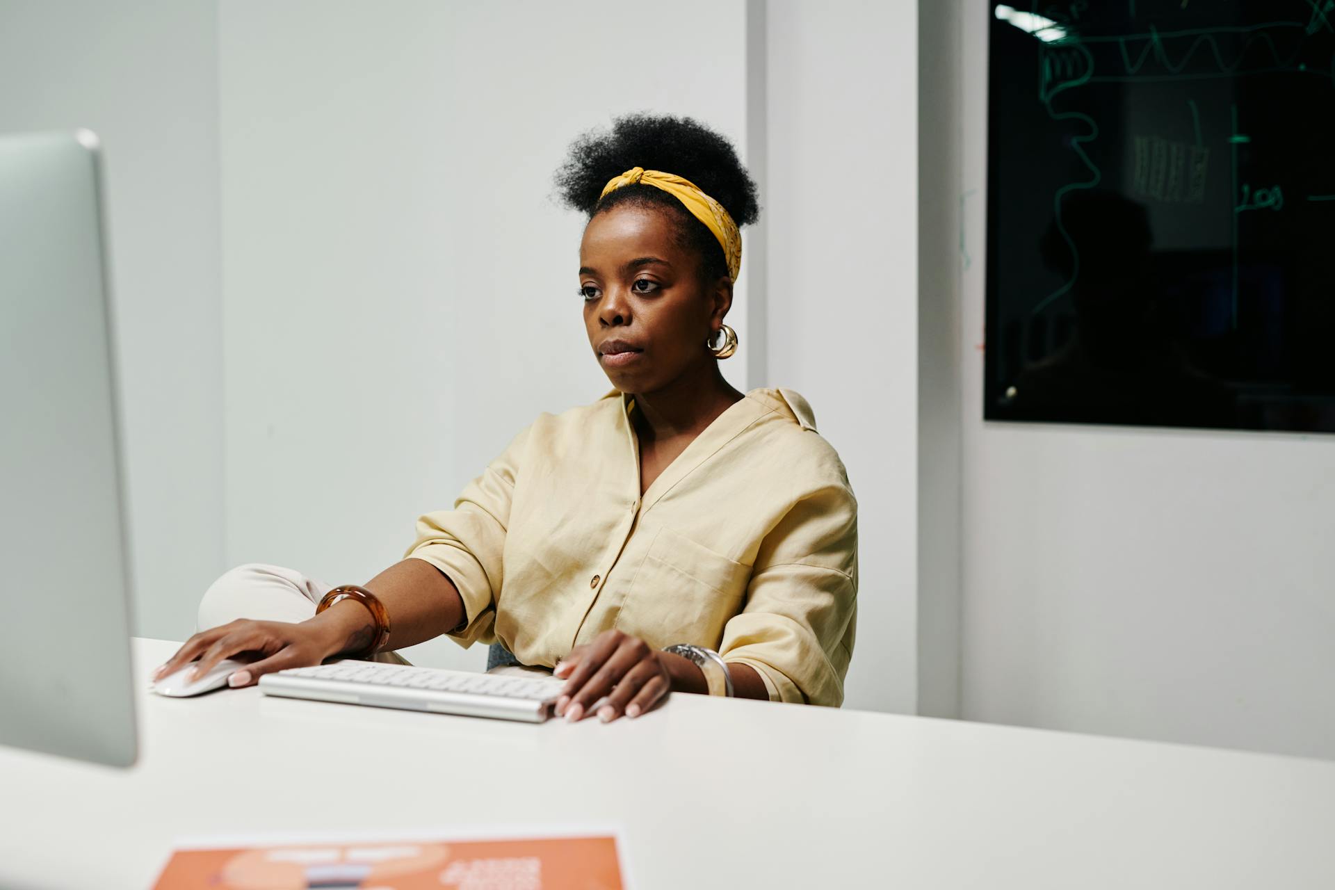 African American woman focused on computer work in a modern office environment.