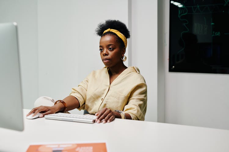 A Woman In Yellow Long Sleeves Using A Computer In The Office