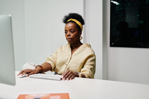 Free African American woman focused on computer work in a modern office environment. Stock Photo