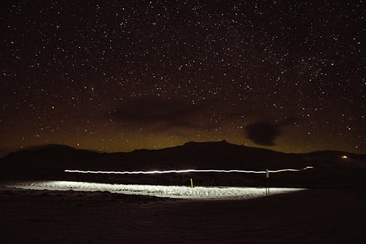 Captivating night landscape with stars and mountains illuminated by light trails.