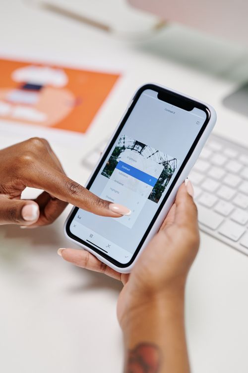 Hands adjust the brightness and contrast of a photo in a phone editing app before it goes out on social media