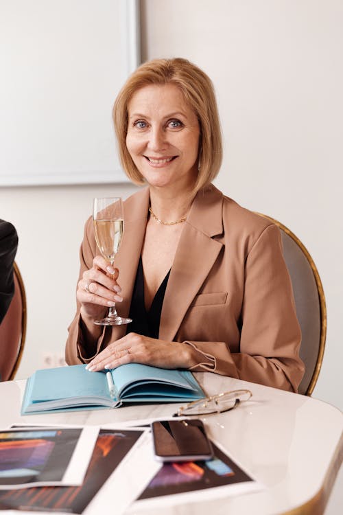 Free A Woman in Brown Blazer Holding a Glass of Wine Stock Photo