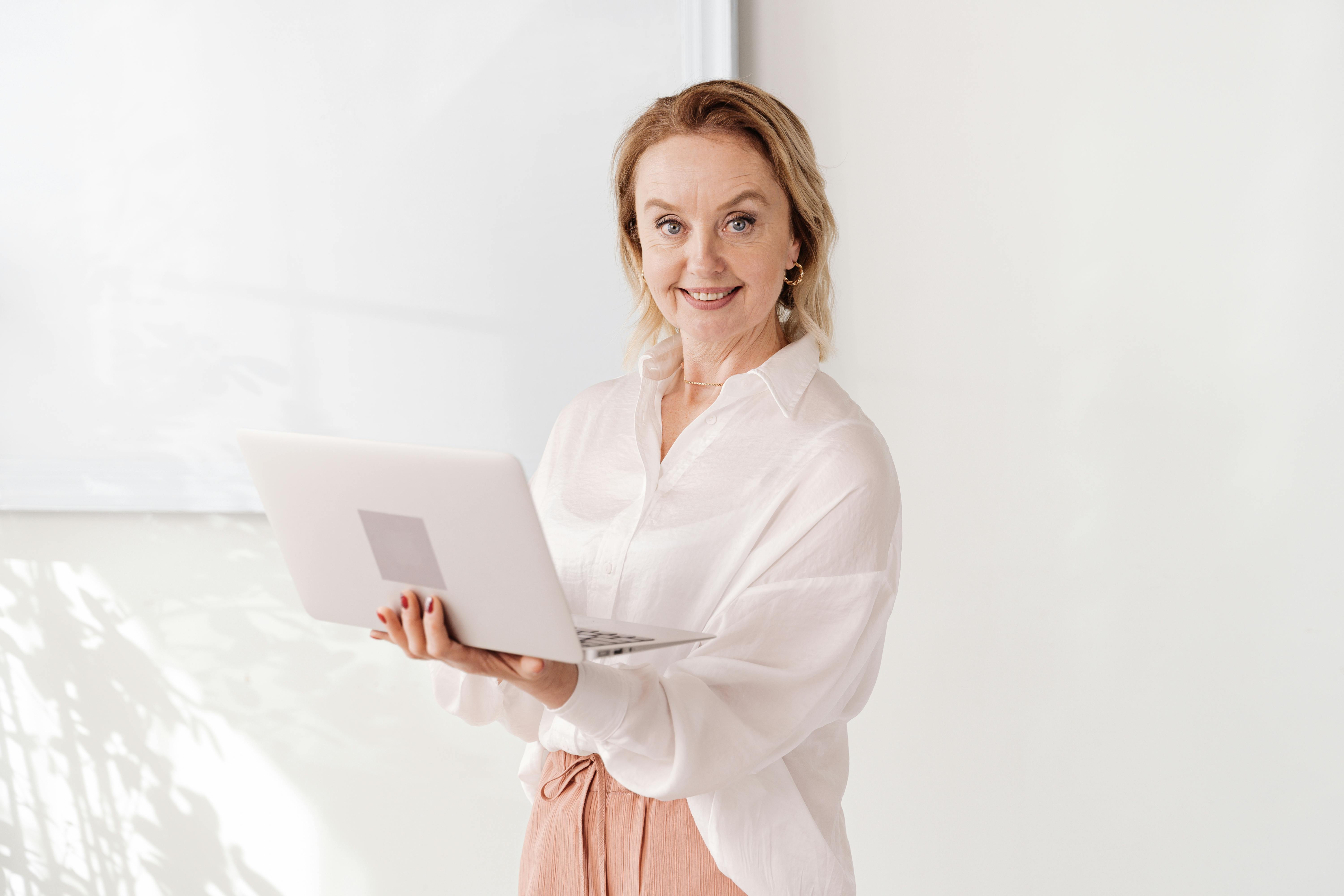 Transformação digital: estratégias para empreendedores de sucesso 3 Confident woman smiling and holding a laptop in a bright, modern office setting.