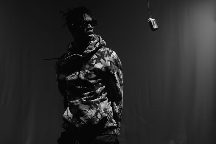 Grayscale Photo Of A Man In Camouflage Hoodie Rapping