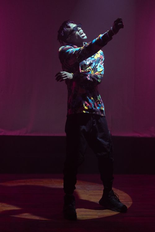Free Energetic black rapper in colorful outfit performing on stage, captured in a vibrant and moody ambiance. Stock Photo