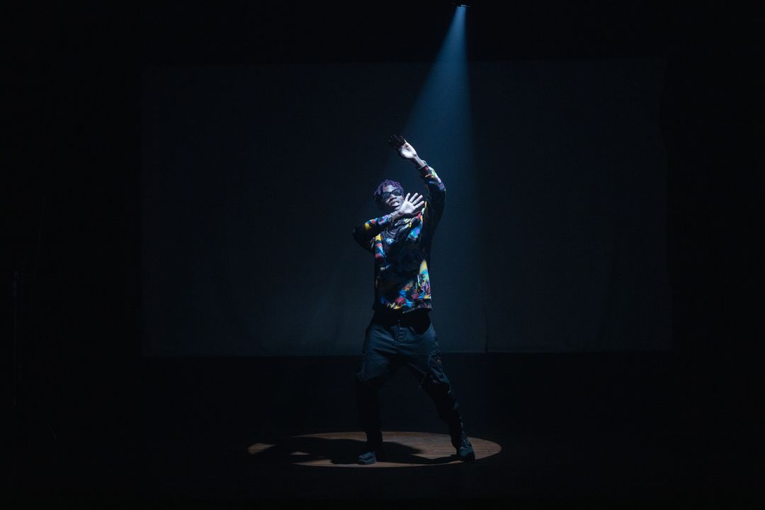 Hip-hop dancer performing under a spotlight on stage
