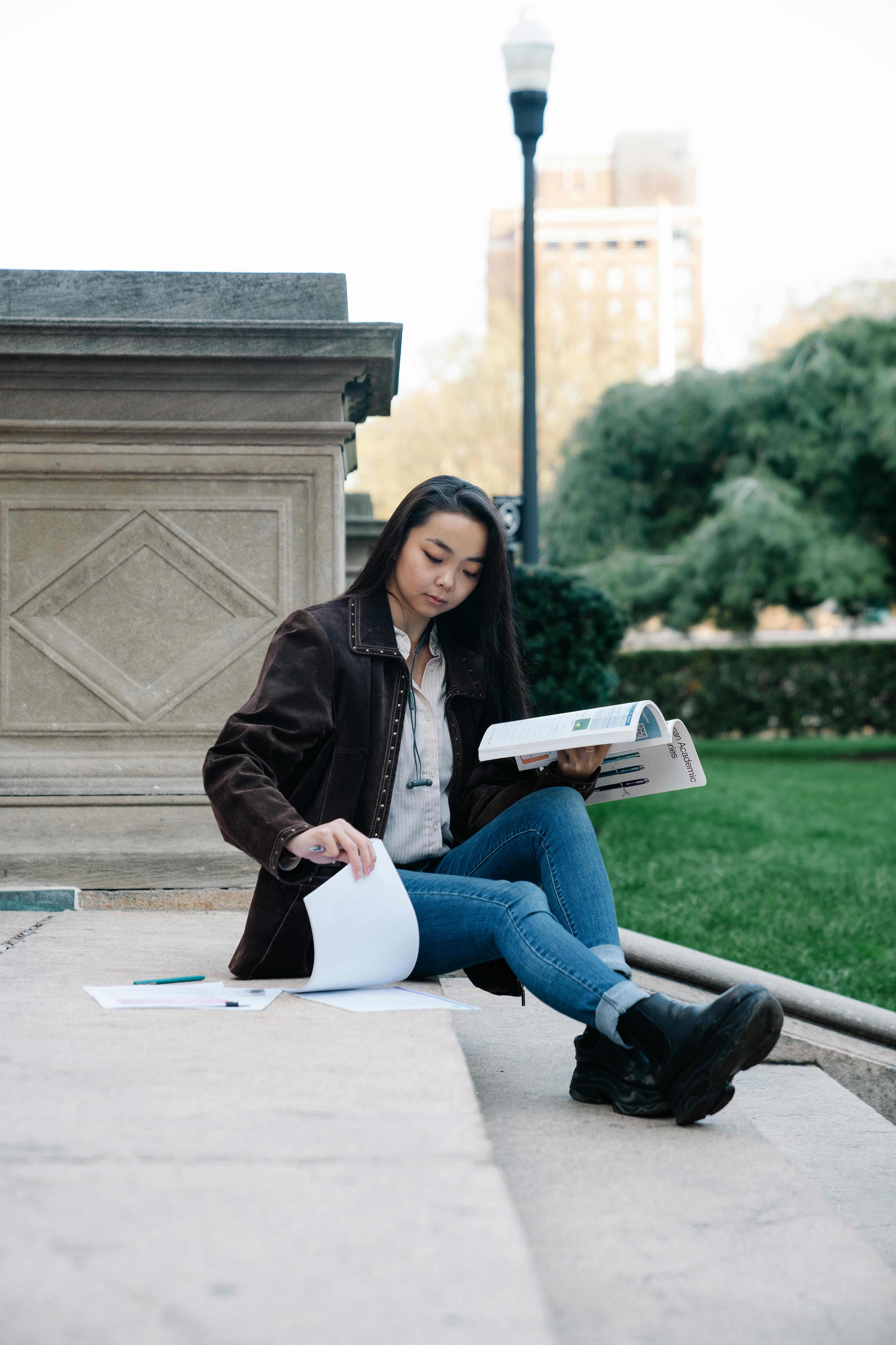 a woman studying while sitting on a concrete staircase