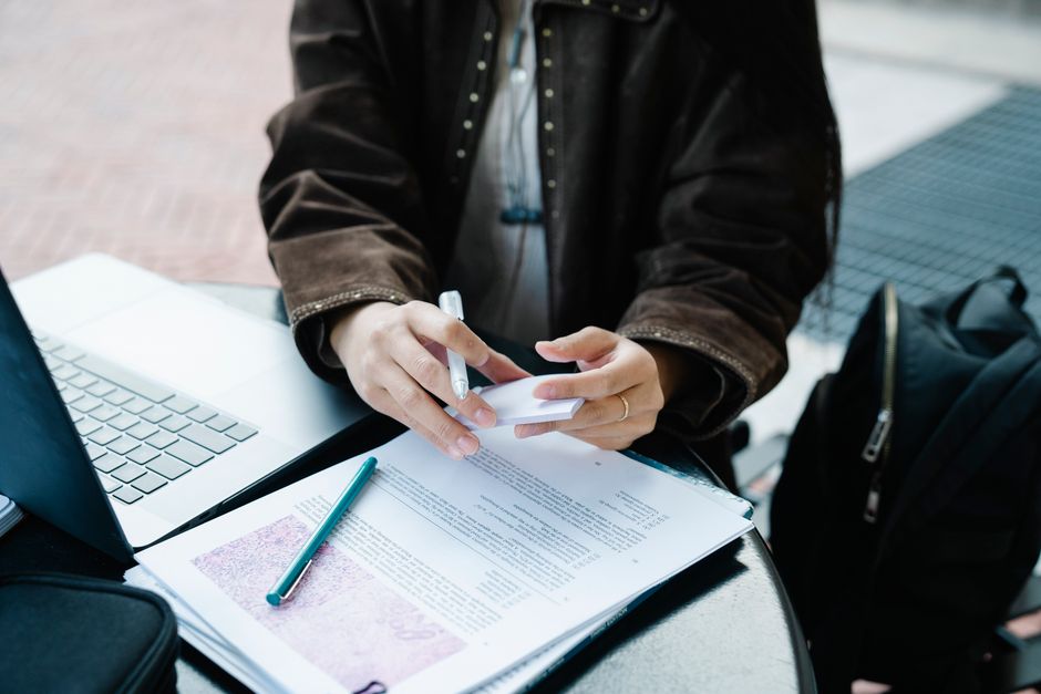An adult engaged with a laptop and documents outside, highlighting productivity and focus. An adult engaged with a laptop and documents outside, highlighting productivity and focus.