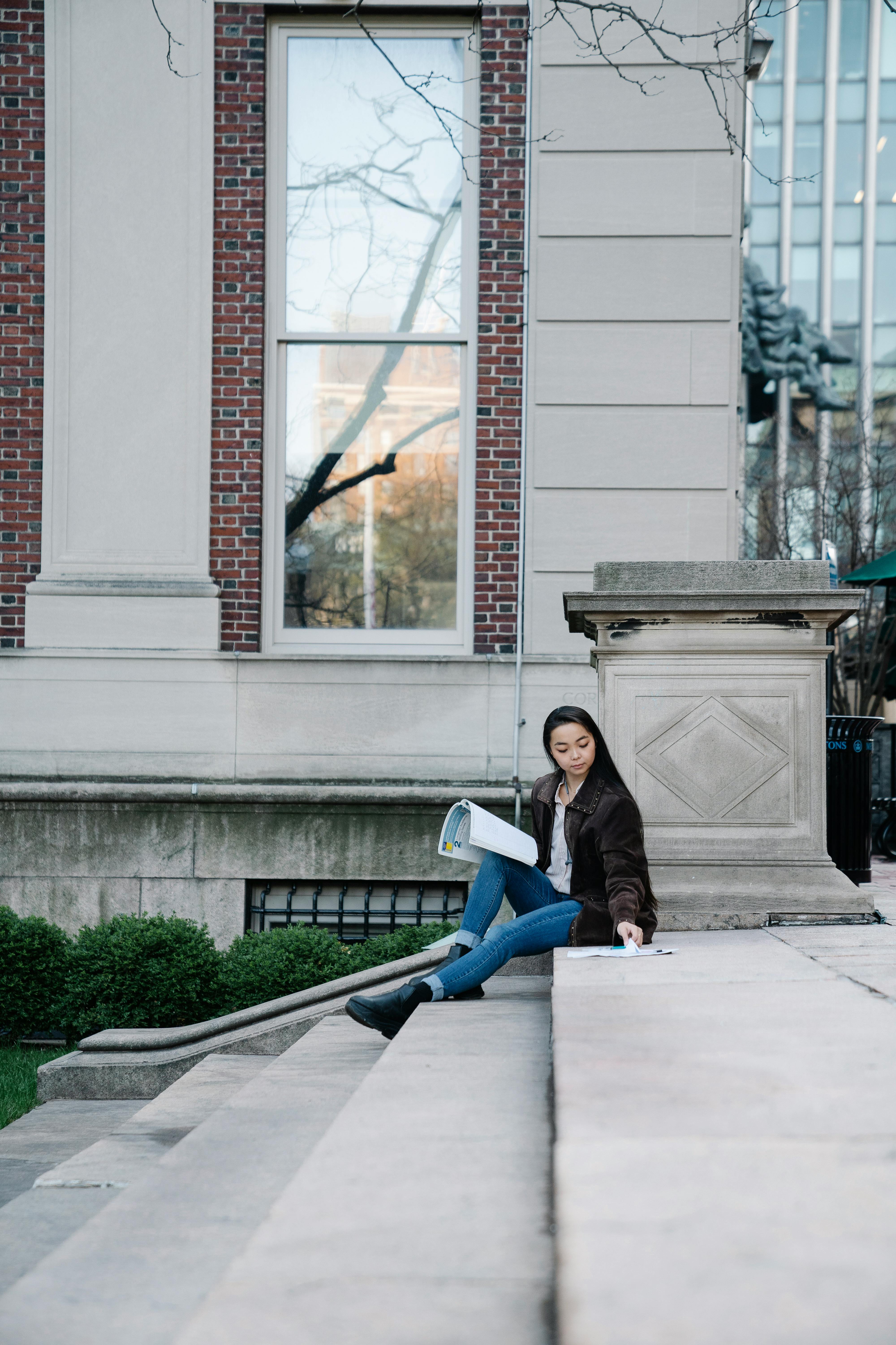 a woman studying while sitting on a concrete staircase