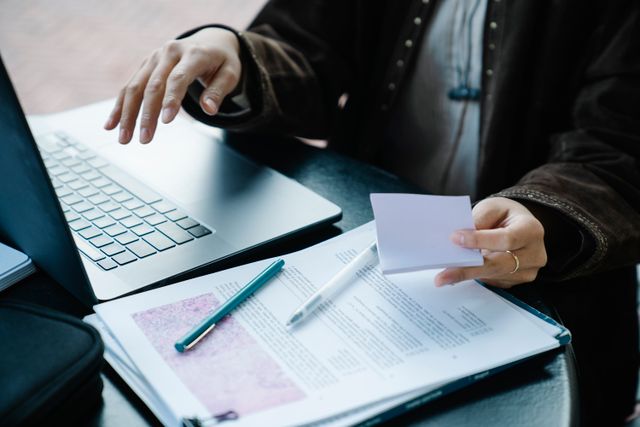 Assistante administrative indépendante travaillant sur un ordinateur portable avec des documents et un stylo