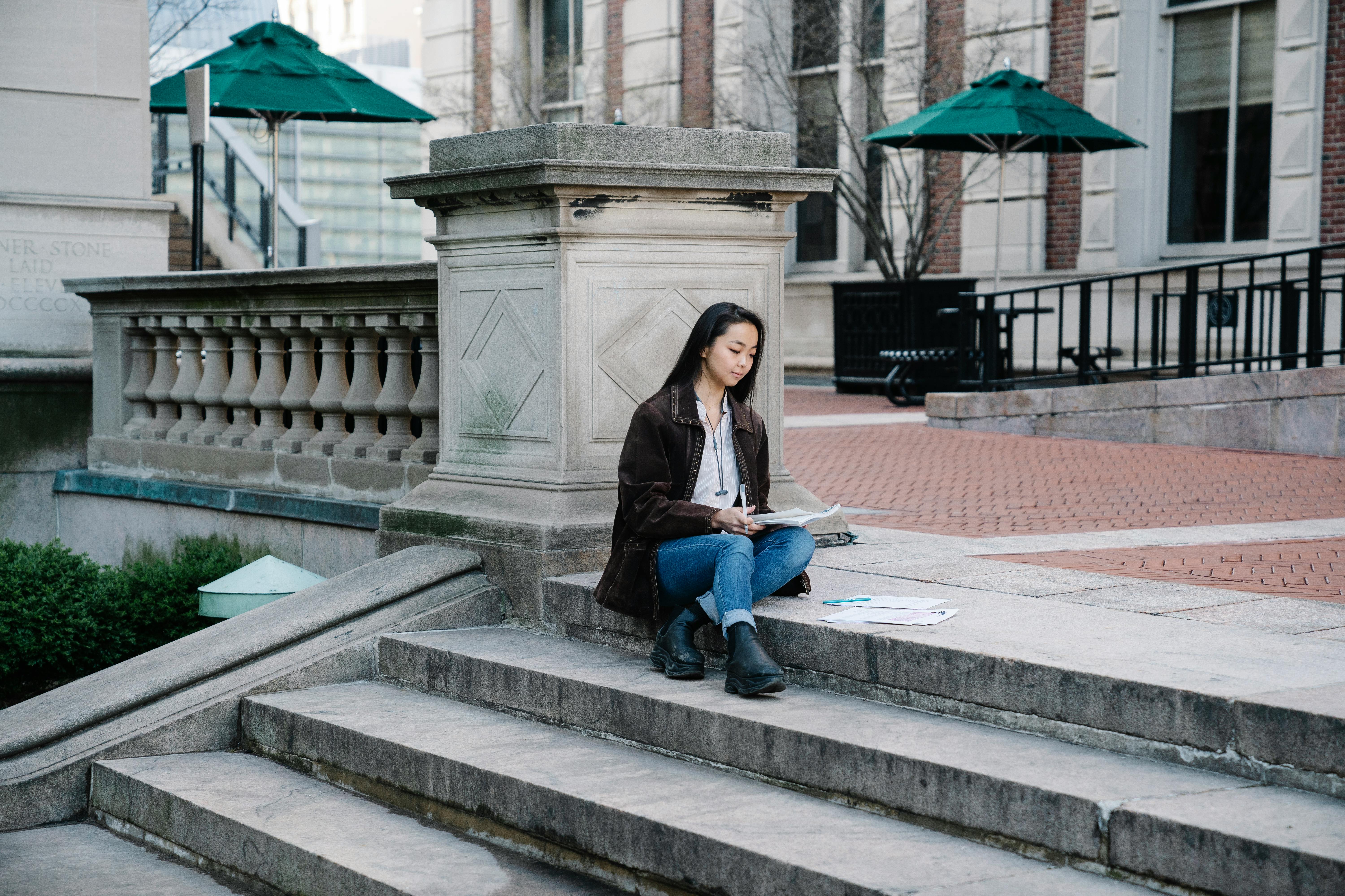 a woman studying while sitting on a concrete staircase