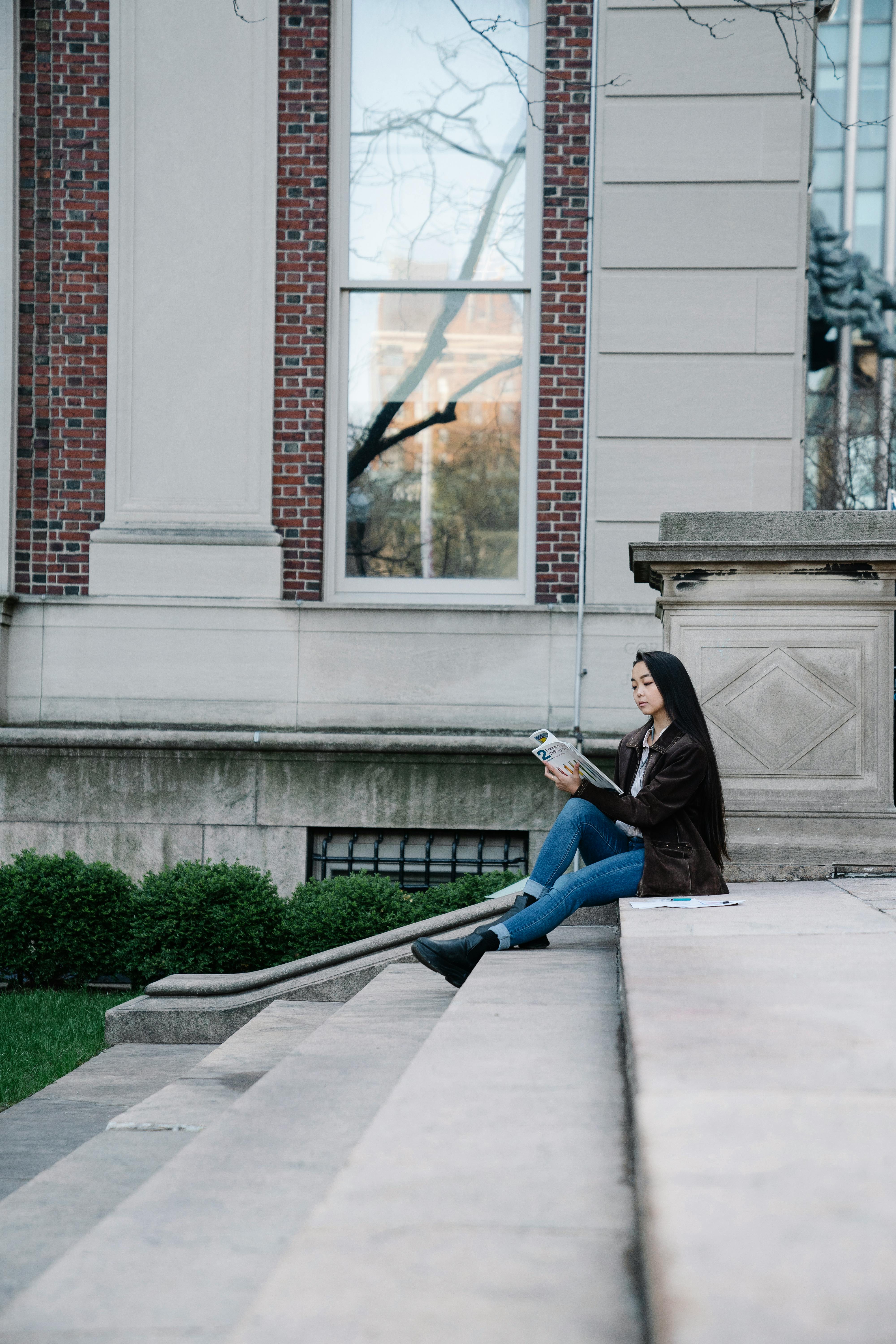 a woman studying while sitting on a concrete staircase